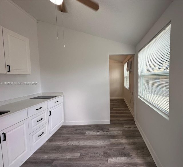 kitchen featuring lofted ceiling, dark wood-style flooring, white cabinetry, and baseboards