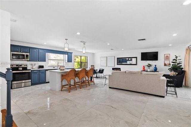 kitchen featuring a breakfast bar, blue cabinetry, stainless steel appliances, light countertops, and visible vents