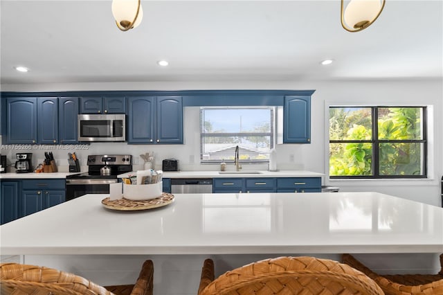 kitchen with stainless steel appliances, light countertops, a sink, and blue cabinetry