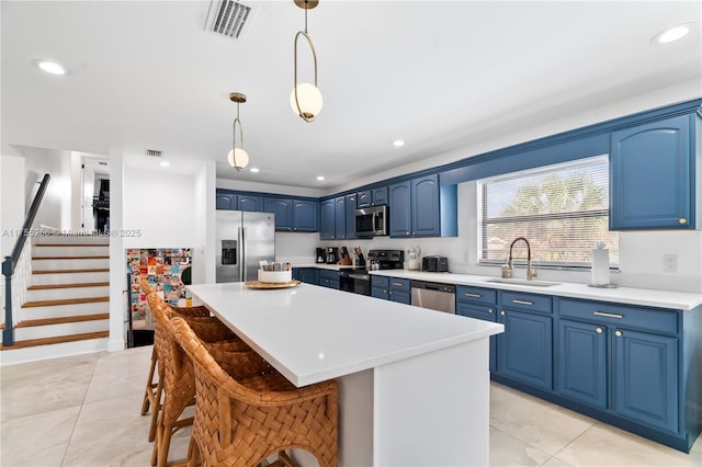 kitchen with visible vents, a center island, blue cabinets, stainless steel appliances, and a sink