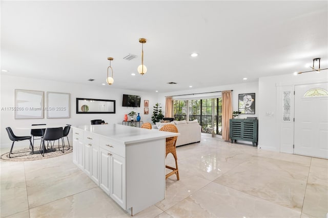 kitchen with a kitchen island, white cabinetry, marble finish floor, light countertops, and pendant lighting