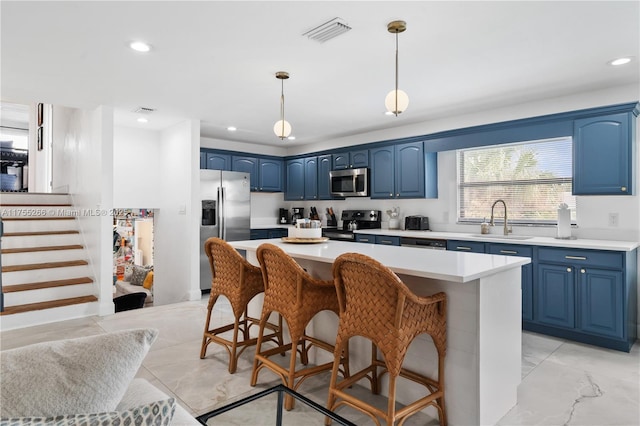 kitchen with appliances with stainless steel finishes, blue cabinets, a sink, and visible vents