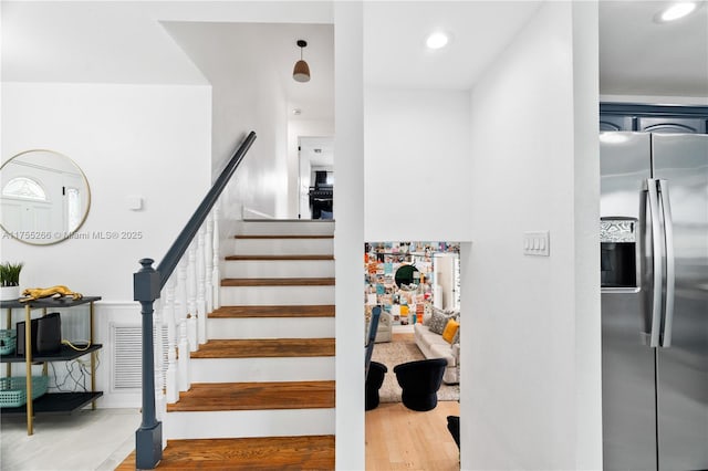 stairway with wood finished floors and recessed lighting