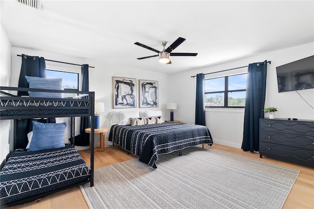 bedroom with ceiling fan, wood finished floors, and visible vents