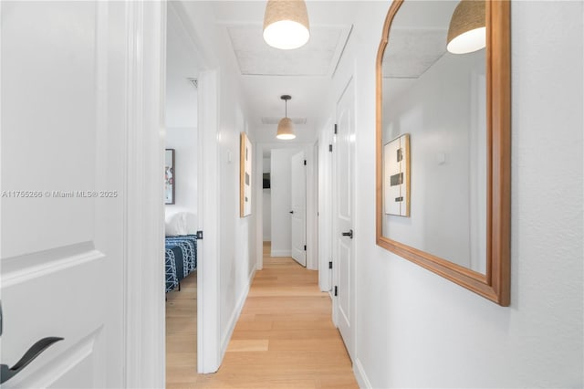 hall featuring visible vents, light wood-style flooring, and baseboards