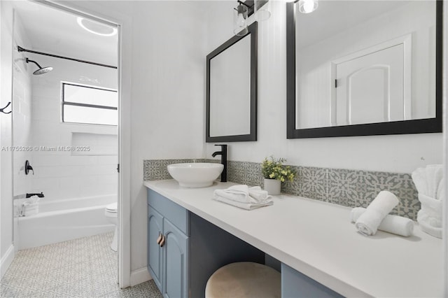 bathroom featuring baseboards, tub / shower combination, vanity, and toilet