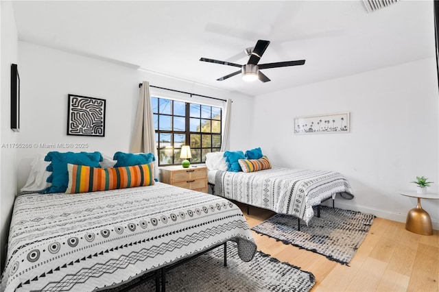 bedroom featuring visible vents, ceiling fan, baseboards, and wood finished floors