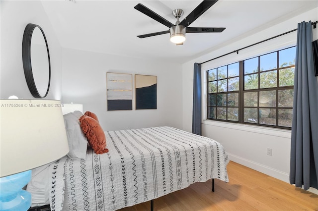 bedroom with ceiling fan, baseboards, and wood finished floors