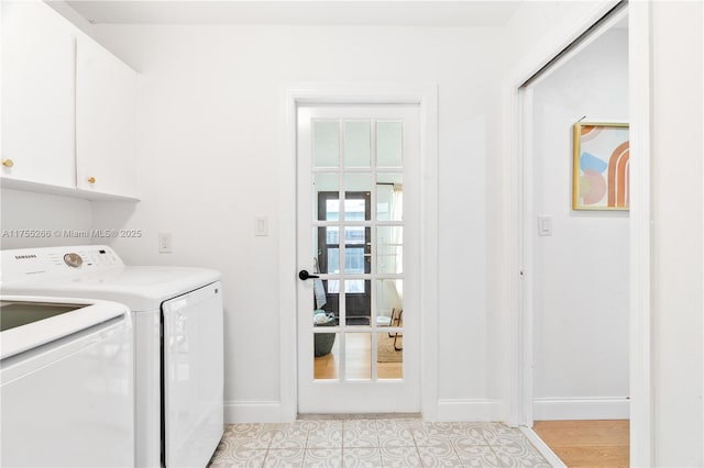 clothes washing area featuring washer and clothes dryer, cabinet space, and baseboards