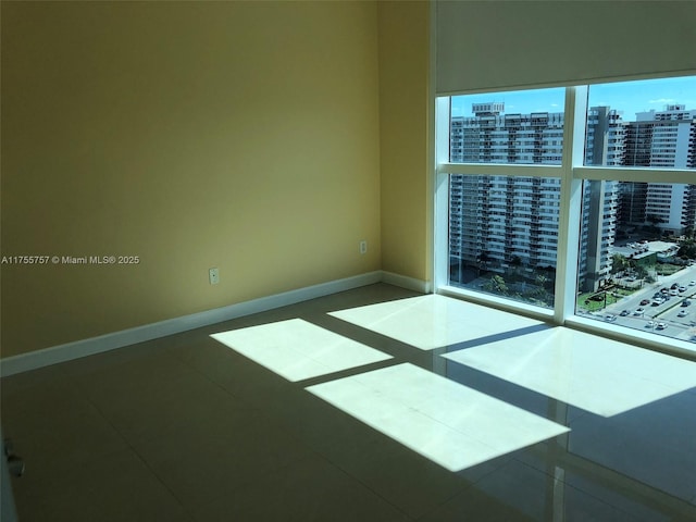 tiled spare room with baseboards and a city view