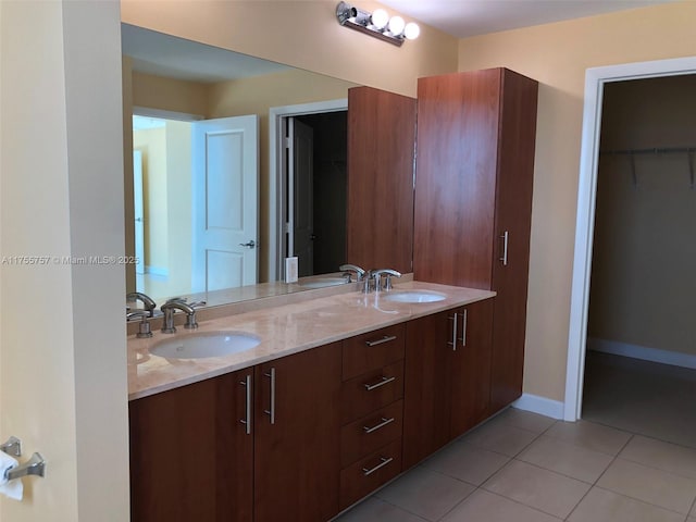 bathroom featuring baseboards, double vanity, a sink, and tile patterned floors