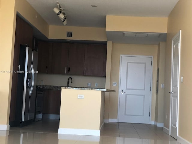 kitchen with a sink, dark brown cabinets, stainless steel fridge with ice dispenser, and light tile patterned flooring