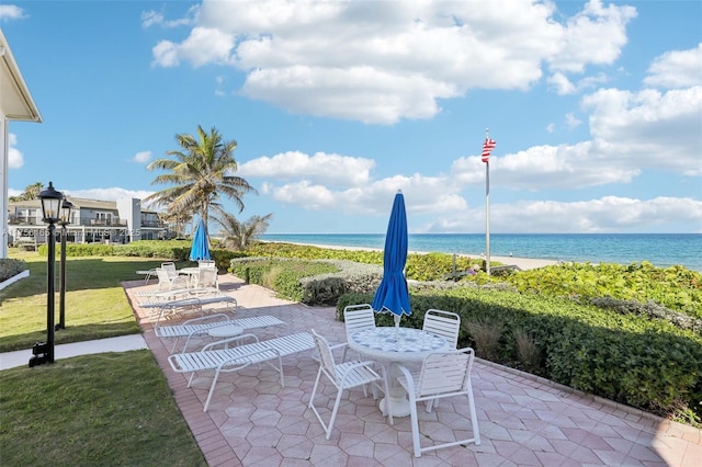 view of patio / terrace with a water view, a beach view, and outdoor dining area