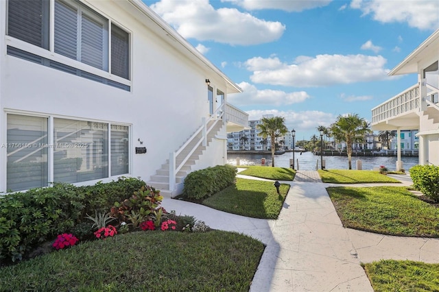 view of yard featuring a dock, a water view, and stairs