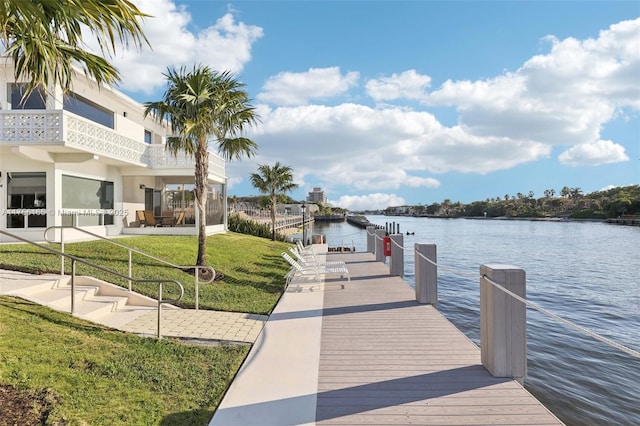 view of dock with a lawn and a water view