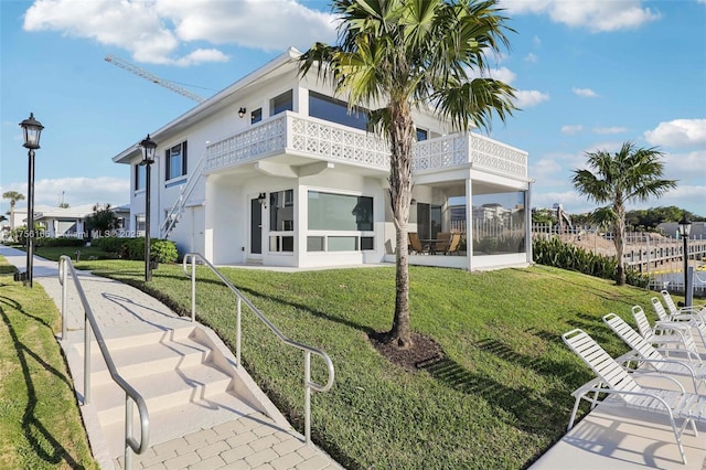 exterior space with a balcony, stucco siding, and a yard