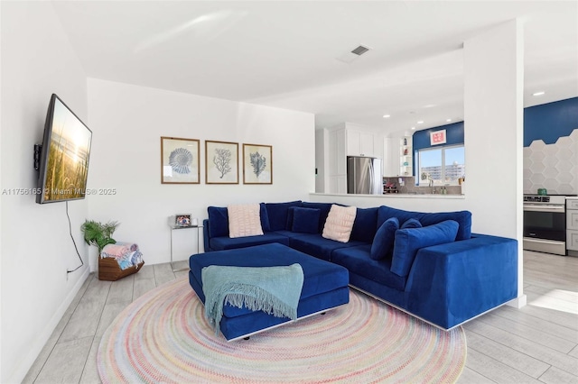 living area with recessed lighting, visible vents, and light wood-style flooring