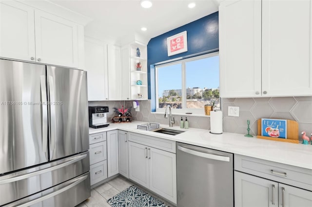 kitchen with open shelves, stainless steel appliances, light countertops, backsplash, and a sink