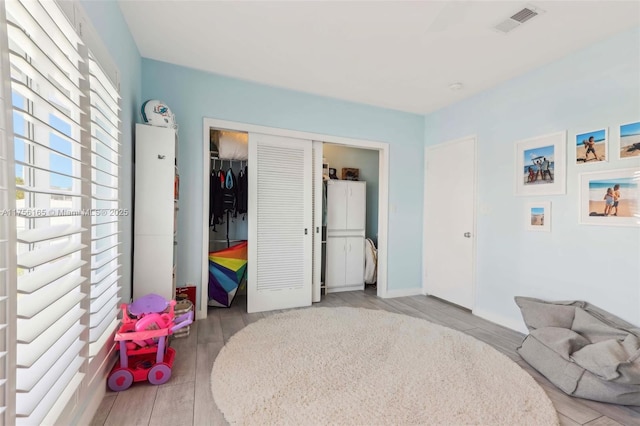 bedroom with a closet, wood finished floors, and visible vents