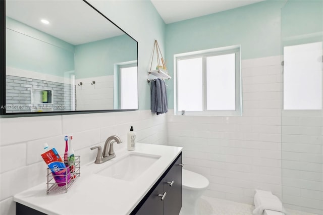 full bathroom with tiled shower, toilet, tile walls, and vanity