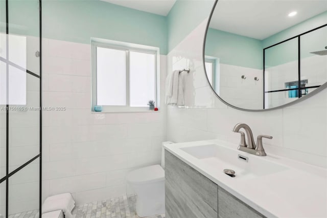 bathroom featuring toilet, a walk in shower, tile walls, and vanity