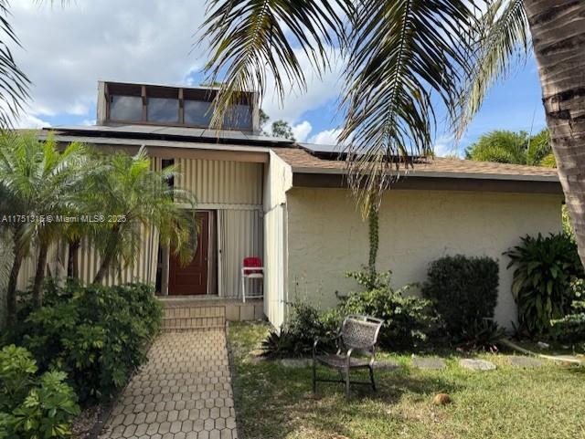 entrance to property with roof mounted solar panels and stucco siding