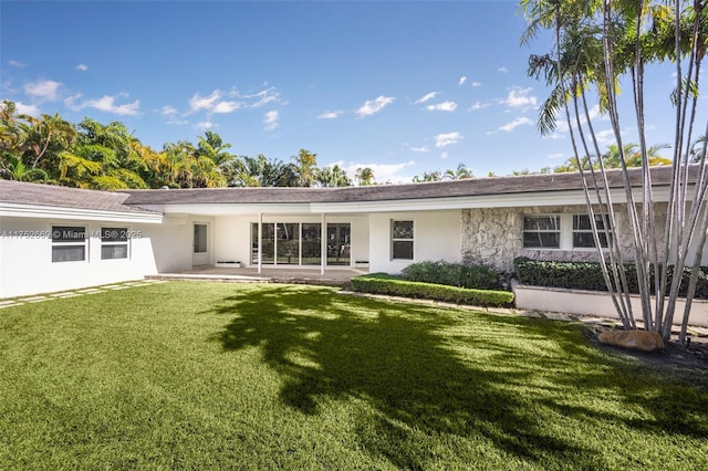 back of property featuring a patio area, stone siding, a lawn, and stucco siding