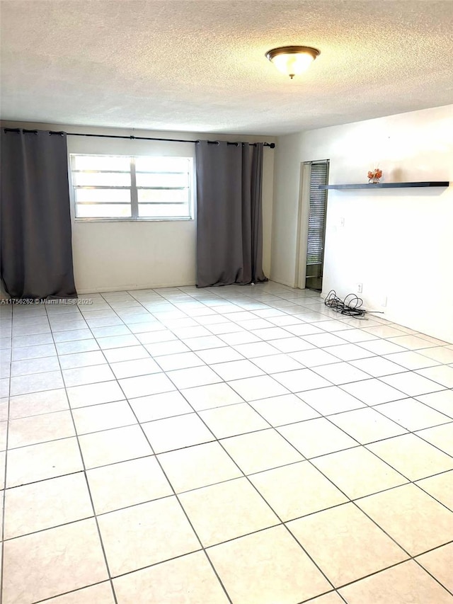 empty room with a textured ceiling and light tile patterned floors