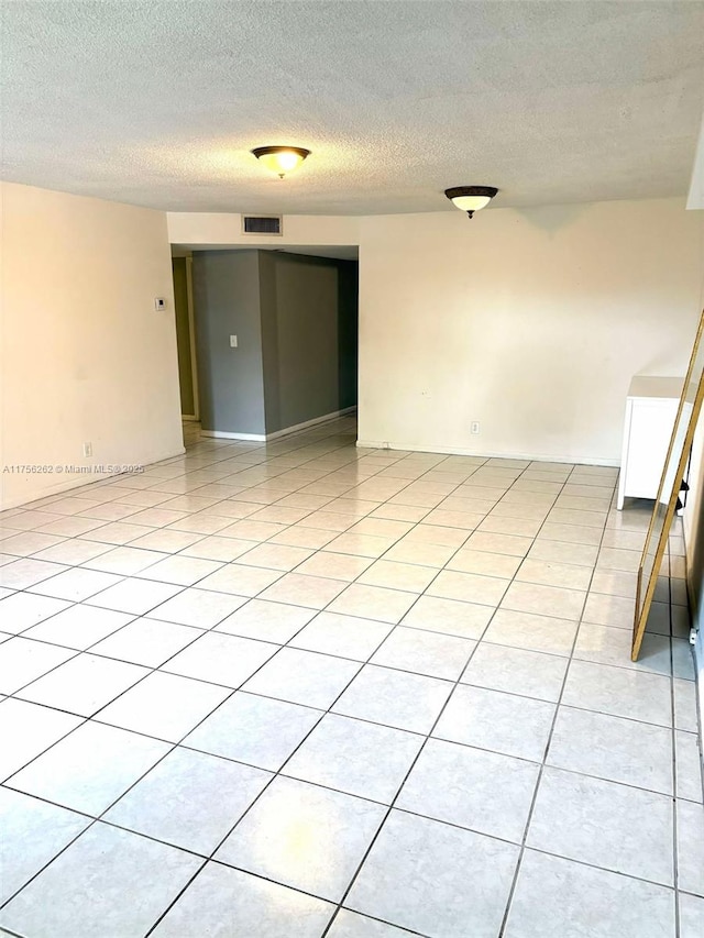 spare room with light tile patterned floors, visible vents, and a textured ceiling