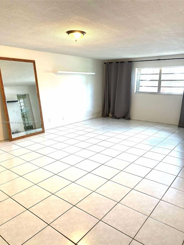 spare room with light tile patterned floors and a textured ceiling