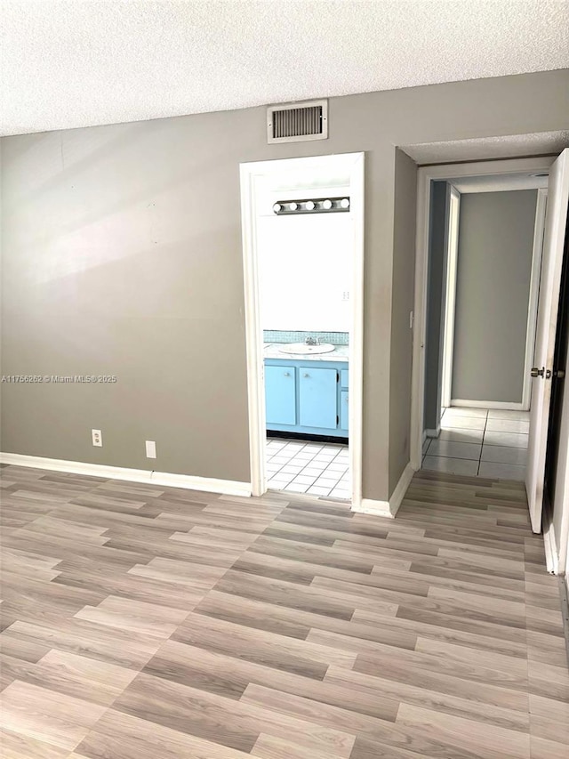 empty room featuring a sink, baseboards, visible vents, and a textured ceiling