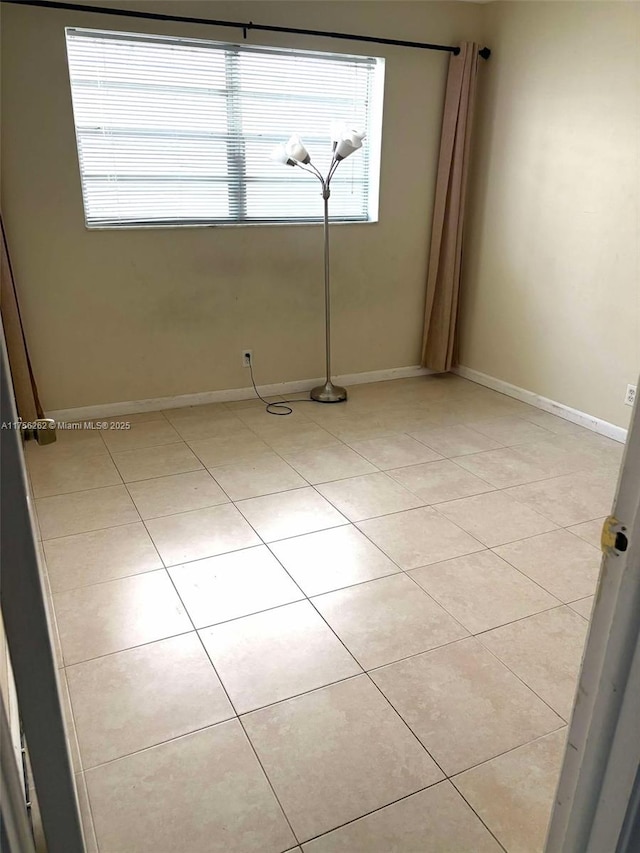 spare room with a healthy amount of sunlight, light tile patterned floors, and baseboards