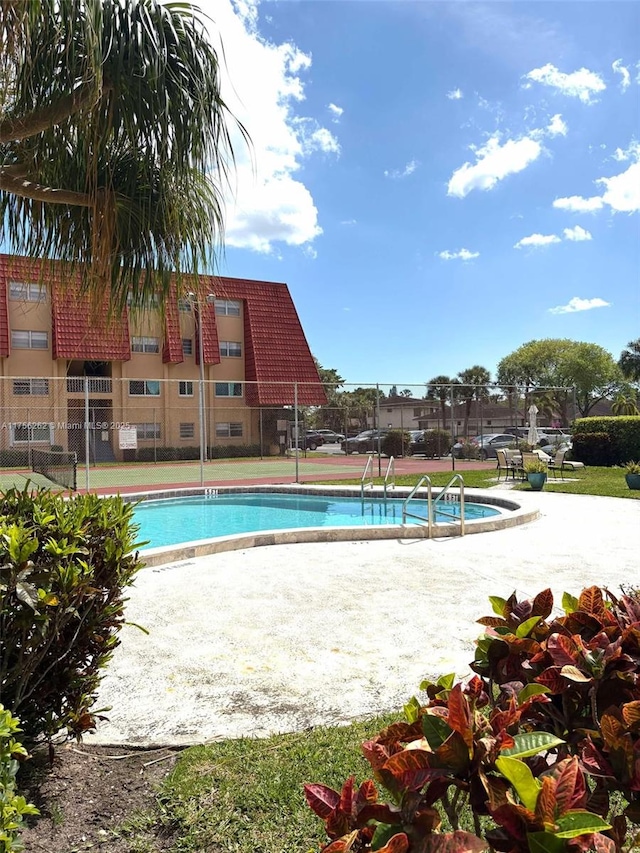 view of pool featuring a tennis court and fence