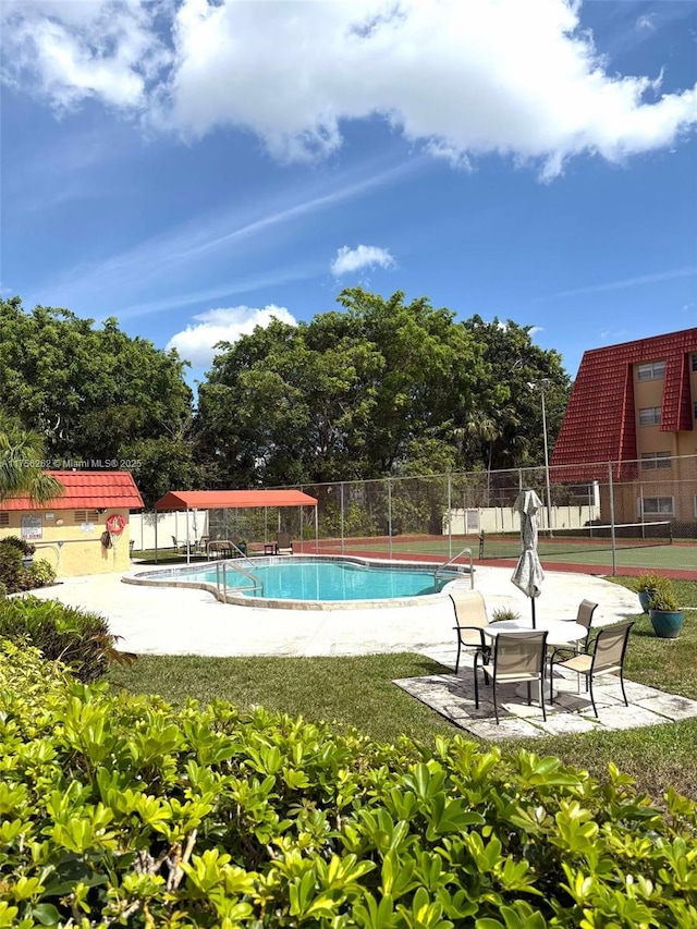 pool with a patio area and fence