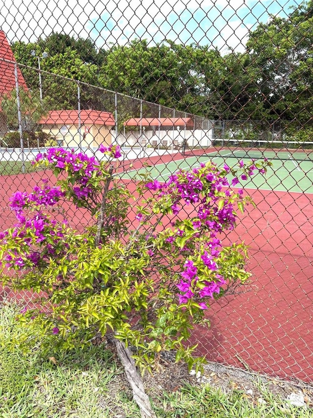 exterior space with a tennis court and fence