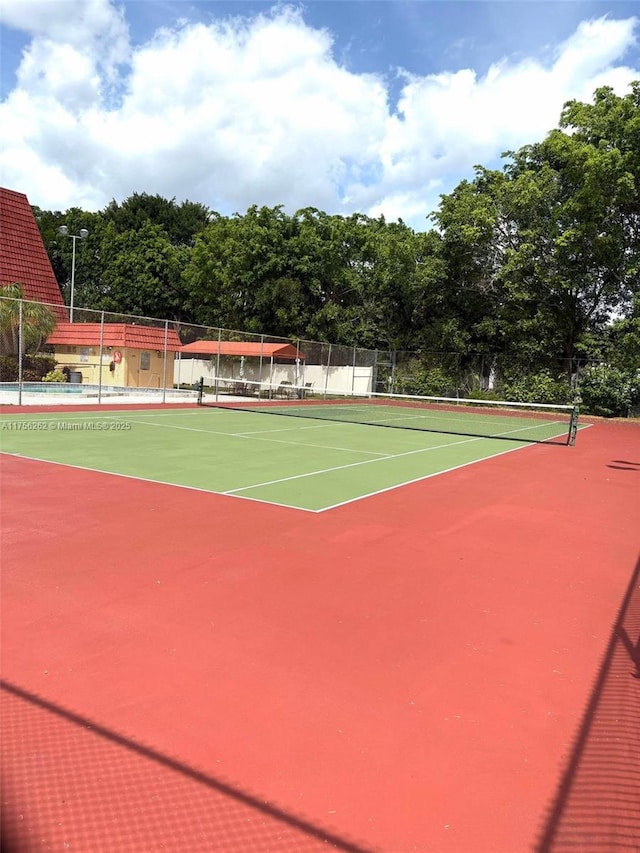 view of tennis court featuring community basketball court and fence