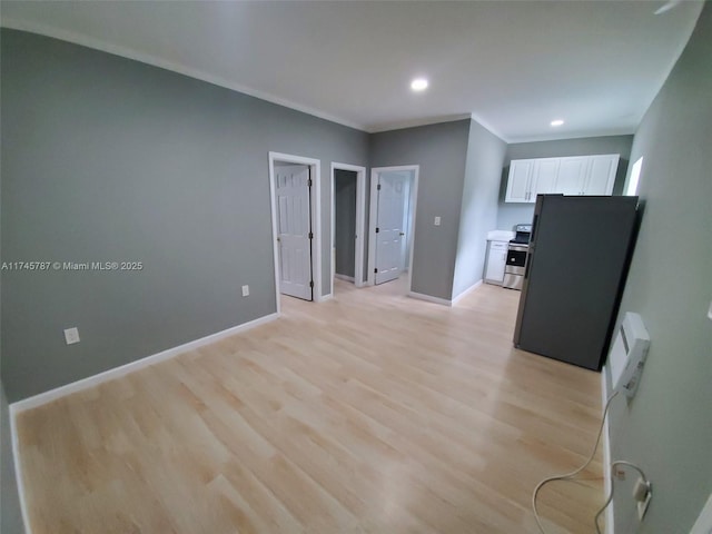 kitchen featuring white cabinetry, baseboards, ornamental molding, light wood-type flooring, and stainless steel range with electric stovetop