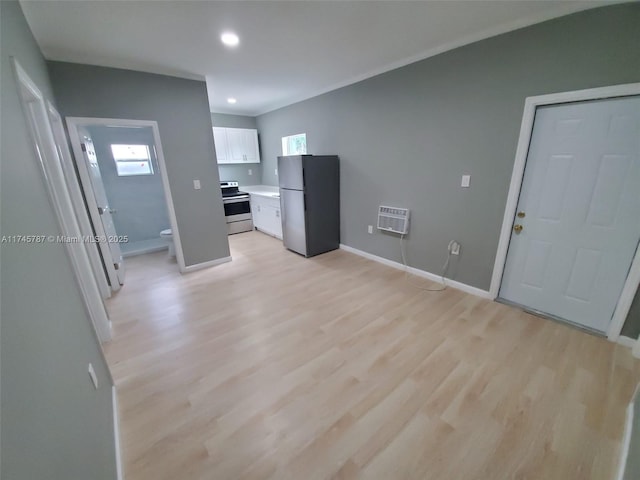 kitchen with white cabinetry, light countertops, freestanding refrigerator, a wall mounted air conditioner, and stainless steel range with electric stovetop