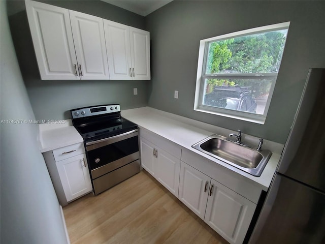 kitchen with light countertops, a sink, stainless steel electric range, and white cabinetry