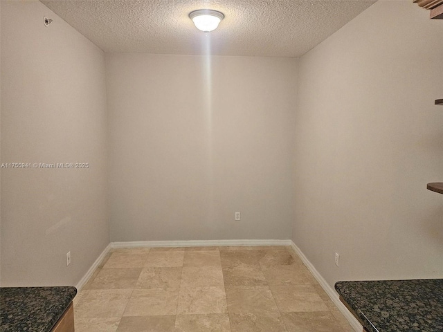 spare room with baseboards and a textured ceiling