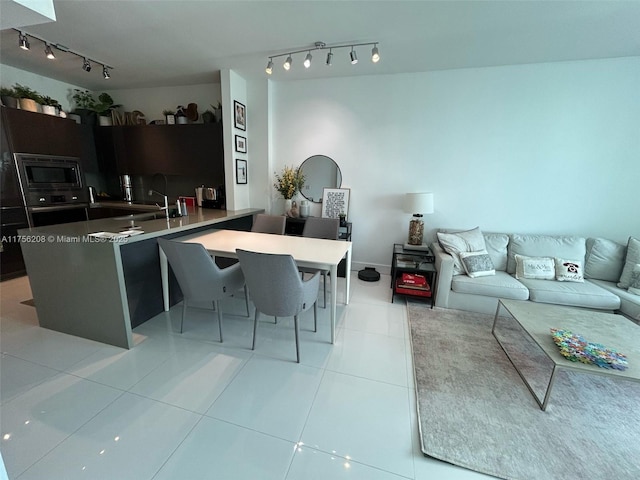 kitchen featuring light tile patterned floors, open floor plan, oven, built in microwave, and a sink