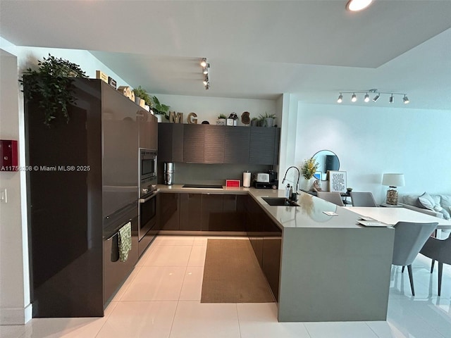 kitchen featuring light tile patterned flooring, a sink, light countertops, appliances with stainless steel finishes, and modern cabinets