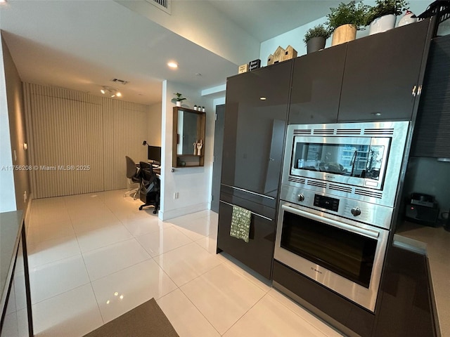 kitchen with light tile patterned floors, appliances with stainless steel finishes, visible vents, and dark cabinetry