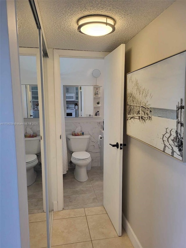 bathroom featuring toilet, tile patterned flooring, and a textured ceiling