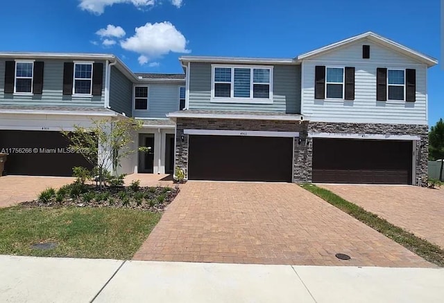 view of front facade with a garage, stone siding, and driveway