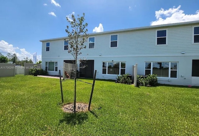 back of property with fence, a lawn, and stucco siding