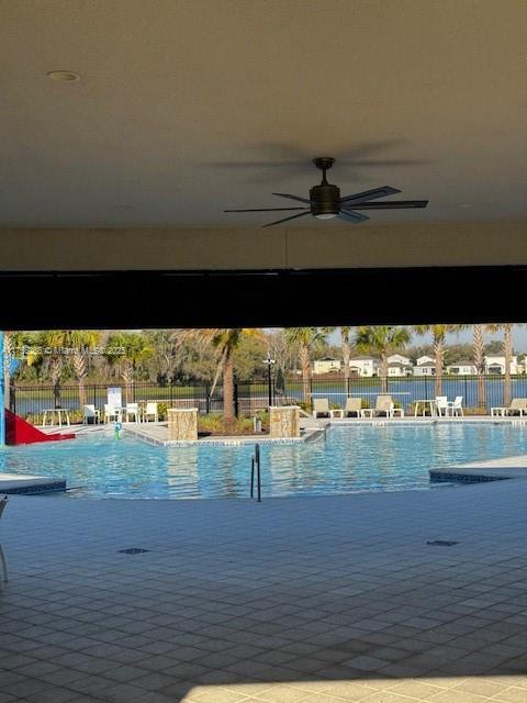 community pool featuring fence and a ceiling fan