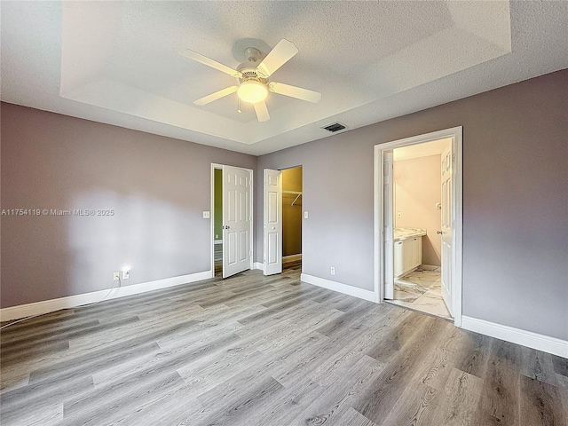 139 Sausalito Dr, Boynton Beach, FL 33436 - unfurnished bedroom with a textured ceiling, visible vents, light wood-style floors, baseboards, and a raised ceiling