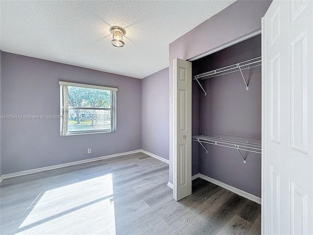139 Sausalito Dr, Boynton Beach, FL 33436 - unfurnished bedroom featuring a textured ceiling, a closet, wood finished floors, and baseboards