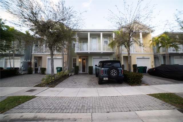 view of property featuring a garage, driveway, a balcony, and stucco siding